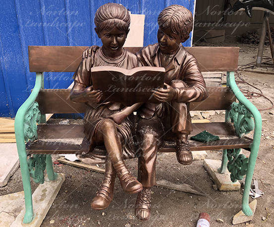 Bronze children statue sitting on bench