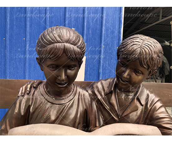 Bronze children statue sitting on bench