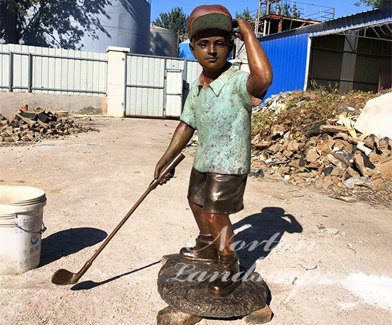 Bronze statue of little boy playing golf